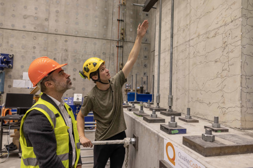 Professor Santiago Pujol and PhD student Charlie Kerby in hard hats and high vis jackets study cracks in concrete wall in the the Seismic Engineering Laboratory.