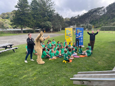 Image of students from Mulberry Grove School in Great Barrier Island outdoors in a field doing ShakeOut drill