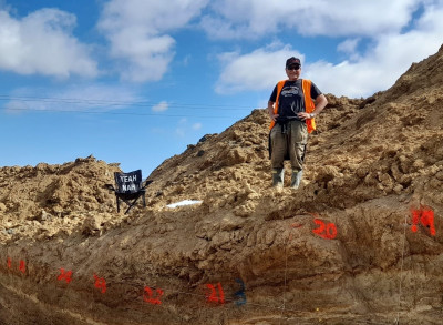 Scientist wearing hi vis vest, next to chair saying Yeah Nah, working on Settlment Fault, Catlins